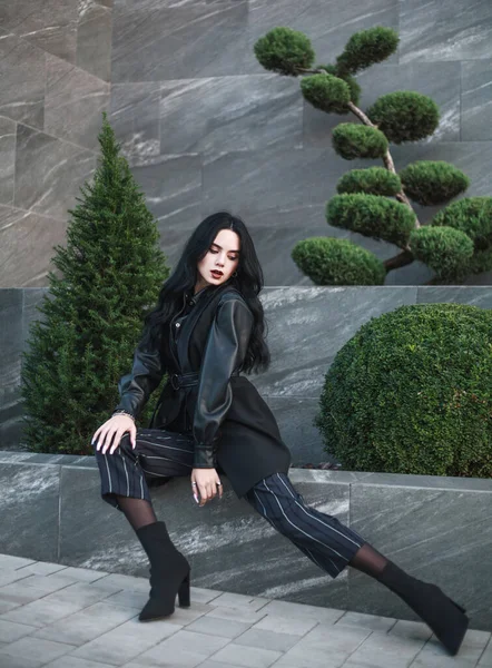 黒い石の壁と緑の植物 未来的なミニマリズムの背景にファッショナブルな服に身を包んだ若い女の子モデル — ストック写真