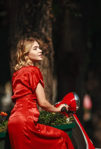 公園でスクーターや花のバスケットと赤いドレスの若い女性 — ストック写真