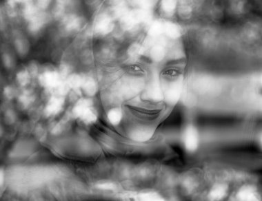 Penceredeki yansımalardan güzel bir kızın yakın plan portresi, siyah beyaz fotoğraf.