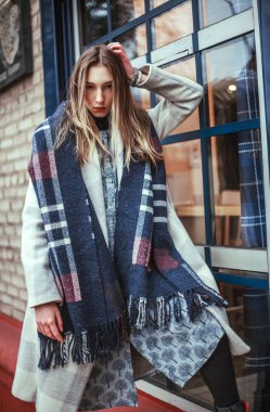 Paltolu genç bir kız ve Avrupa şehrinin caddesinde uzun bir eşarp, şık bir moda tarzı var.