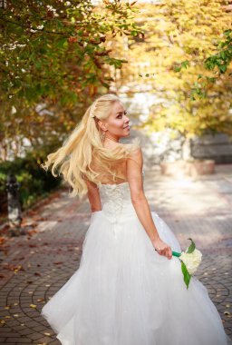 Beyaz elbiseli hayalperest gelin ve bir buket çiçekle neşe dolu bir olayın beklentisiyle