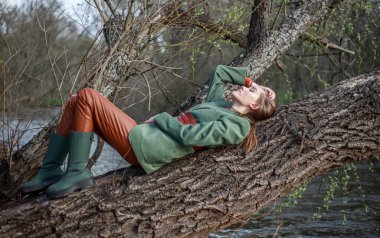 Nehrin kıyısındaki ağaçta kırsal tarzda giyinmiş güzel bir bayan.