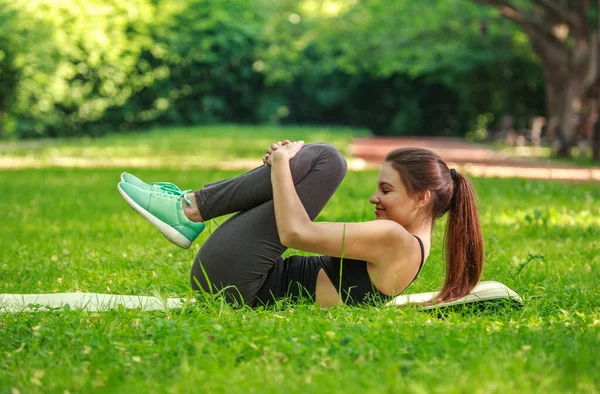 草の上の緑の公園で体を伸ばしフィットネス演習を行う若い女性 自然の中で健康的なライフスタイル — ストック写真