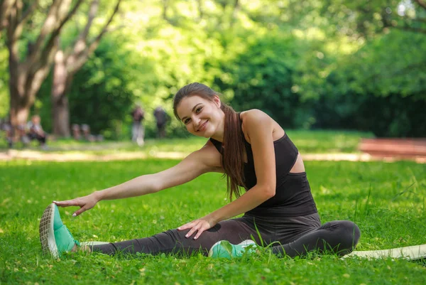 Νεαρή Γυναίκα Κάνει Ασκήσεις Γυμναστικής Τεντώνοντας Σώμα Ένα Πράσινο Πάρκο — Φωτογραφία Αρχείου
