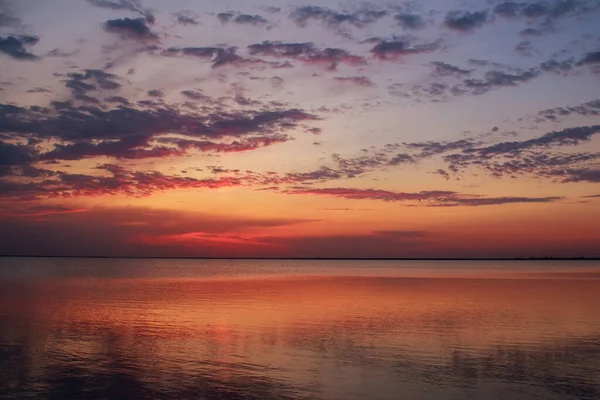 Verträumt Und Dramatisch Farbenfroher Sonnenuntergangshimmel Über Ruhiger Wasseroberfläche Mit Wolkenreflexionen Stockbild