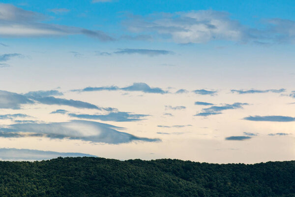 Идиллический горный ландшафт зеленый лес на фоне облаков и синего неба