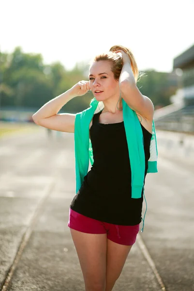 Unga sportiga kvinnan på morgonen med hörlurar på löpband — Stockfoto