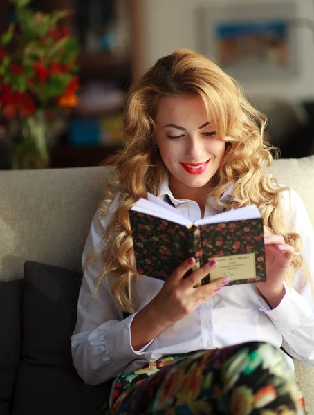Szczęśliwa młoda kobieta czyta książkę na kanapie w domu — Zdjęcie stockowe