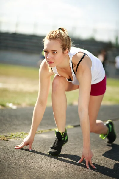 Mladá žena na běžícím pásu je připraven ke spuštění, cvičení venkovní — Stock fotografie