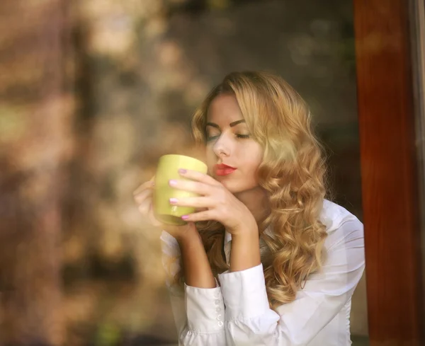 Mujer bebiendo café en el interior, disfrutando del aroma de la bebida —  Fotos de Stock