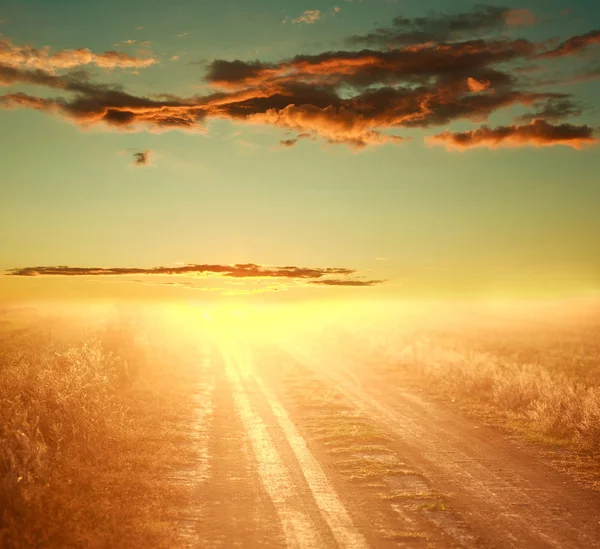Colorato tramonto sulla strada di campagna sul cielo drammatico — Foto Stock