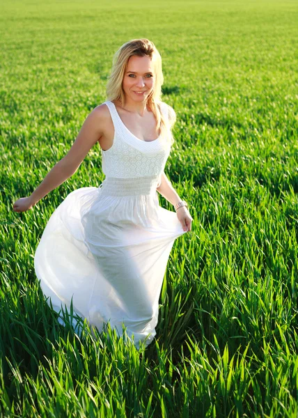 Mulher romântica em vestido branco correndo através do campo verde — Fotografia de Stock