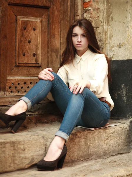 Jong meisje buiten verdrietig, zittend op de achtergrond een oud huis — Stockfoto