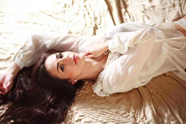 Gorgeous young brunette woman relaxing lying in lingerie on bed — Stock Photo, Image