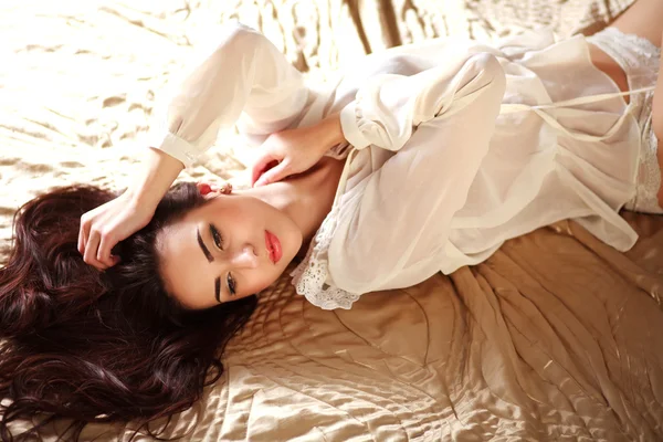 Gorgeous young brunette woman relaxing lying in lingerie on bed — Stock Photo, Image