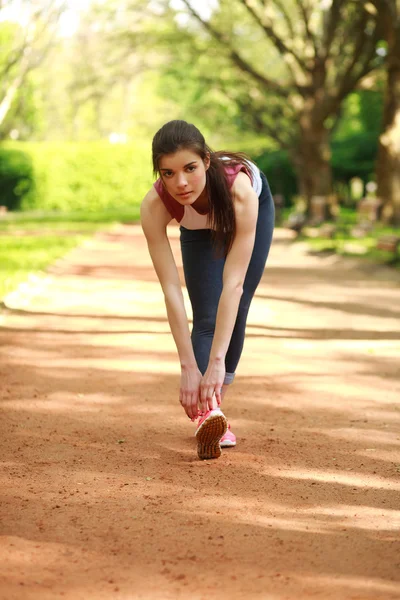 Sprawny dziewczyna ćwiczeń odkryty w lato park przed biegiem — Zdjęcie stockowe