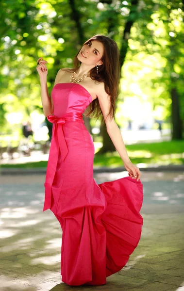 Счастливая девушка в роскошном длинном платье в летнем парке — стоковое фото