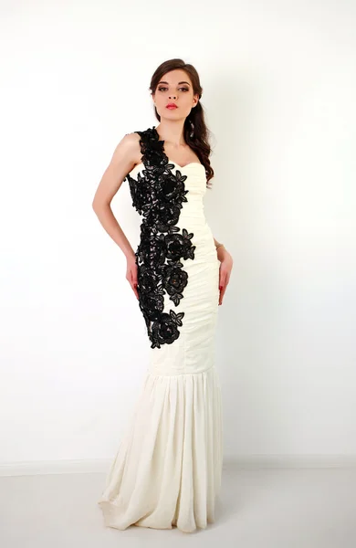 Mode brunette vrouw in lange jurk in studio op wit — Stockfoto