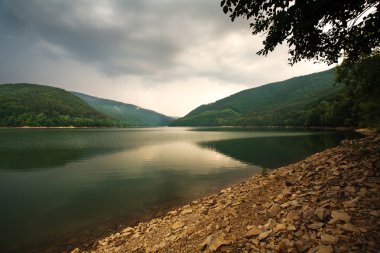 Dağ gölü dramatik gökyüzü arka plan üzerinde yeşil orman