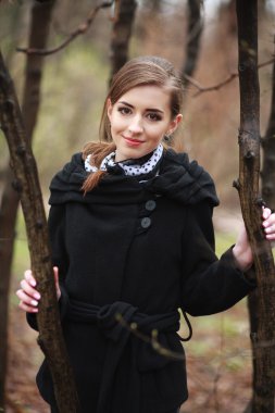 Gülümseyen bir siyah ceket sonbahar parkta genç kadın