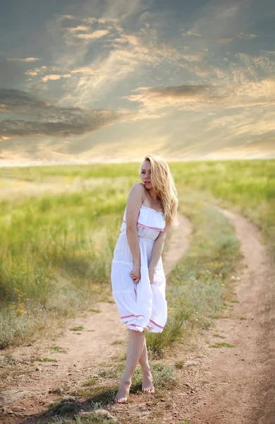 Ragazza sensuale in abito sulla strada di campagna sul cielo drammatico — Foto Stock