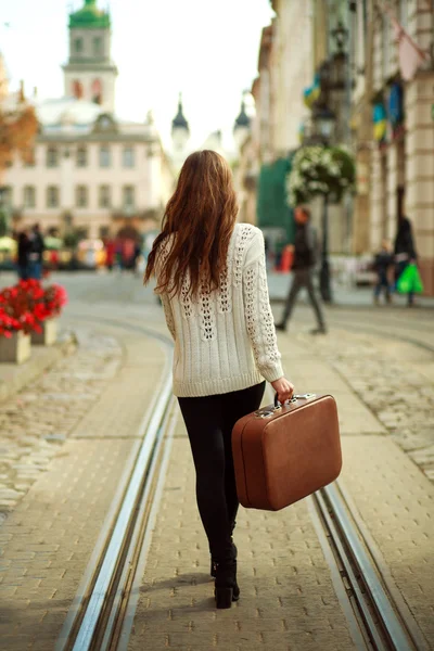Jonge vrouw met een koffer wandelen door de straten — Stockfoto