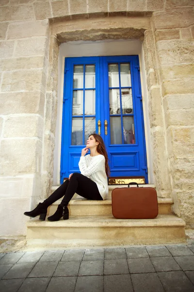 Vrouw reiziger met een koffer dromerige achter zijn huis — Stockfoto