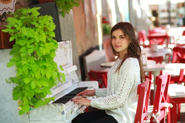 Romantisk flicka som leker på ett gammalt piano i gatan café — Stockfoto