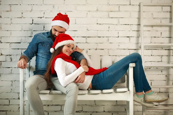 Pareja de ensueño con sombreros rojos de Navidad sentados en el banco — Foto de Stock