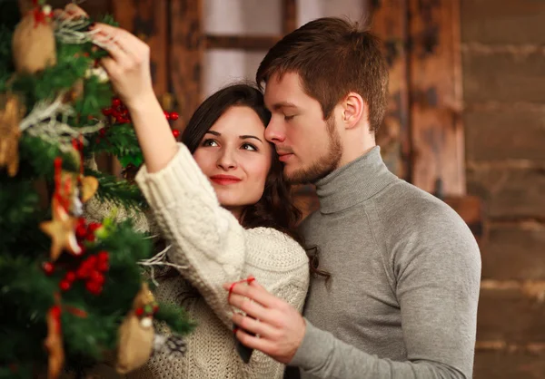 Ungt par i kärlek dekorerar en julgran hemma — Stockfoto
