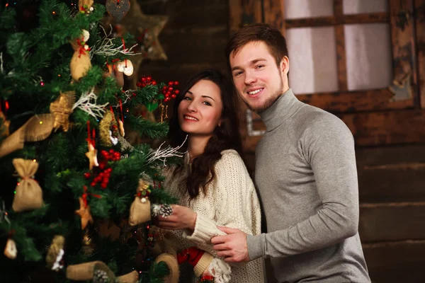 Jovem casal apaixonado decora uma árvore de Natal em casa — Fotografia de Stock