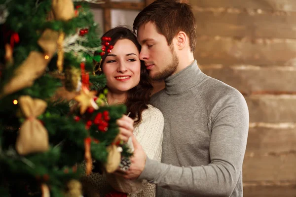 Young couple in love decorates a Christmas tree at home — Stock Photo, Image