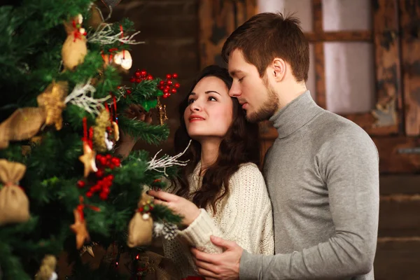 Jovem casal apaixonado decora uma árvore de Natal em casa — Fotografia de Stock