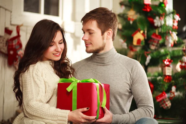 Casal feliz com presente em casa em um contexto do Natal — Fotografia de Stock