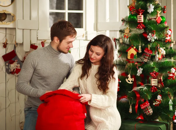 Lyckliga par med gåva hemma på en bakgrund av jul — Stockfoto