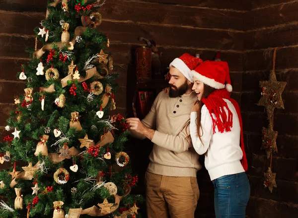 La coppia allegra decora un albero di Natale in una casa di campagna — Foto Stock