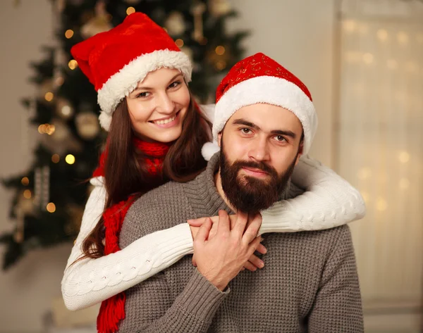 Glückliches Paar auf dem Hintergrund des Weihnachtsbaums zu Hause — Stockfoto