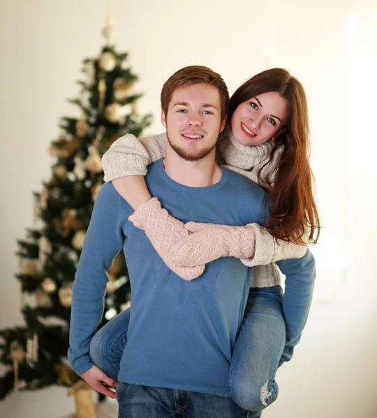 Feliz pareja de invierno en el amor en casa en el fondo del árbol de Navidad —  Fotos de Stock