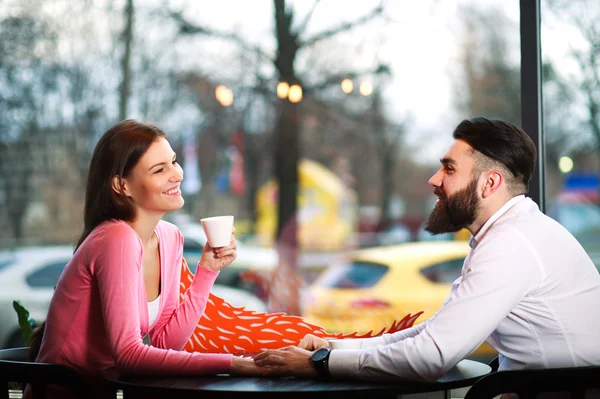 Unga lyckliga par i kärlek i café hand i hand — Stockfoto