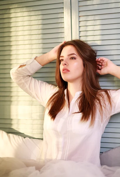 Dreamy young woman at home on bed in sunlight from window — Stock Photo, Image