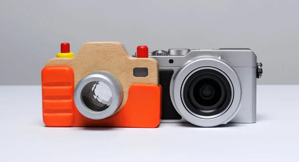 A wooden camera, an educational toy on the background of a compact modern digital camera ...