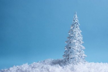 Mavi arka planda kar üzerinde buzlu Noel ağacı. Sıcak, büyülü kış tatili atmosferi. Kış arkaplanı.
