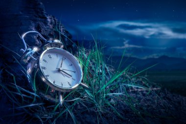 Alarm clock on grass at night clipart