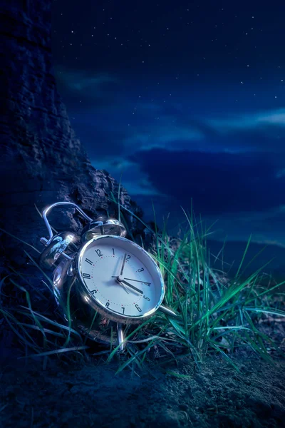 Reloj despertador en hierba por la noche — Foto de Stock