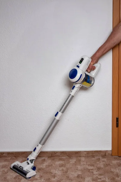休暇中の人 男はコードレスバッテリー駆動の掃除機で部屋にカーペットをきれいにします 家の活動 行動中のフーバー — ストック写真