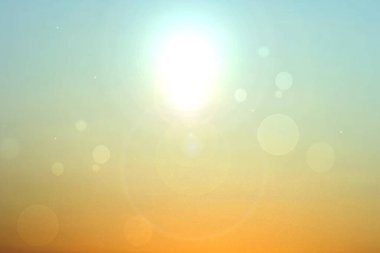 Soyut çöl manzarası, sarı kum tozu ve mavi turkuaz gökyüzü ve bokeh daireleriyle parıldayan bir güneş. Güzel bir doku. Seyahat ve turizm reklamı.