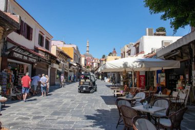 RODES, Yunanistan - 07 Haziran 2021. Mayıs ayı sonuna kadar Corona 'daki tecritten sonra, ilk turistler eski Rodos kasabasındaki ünlü Sokrates Caddesi boyunca tekrar yürüdüler. Restoranların çok az misafiri olur..