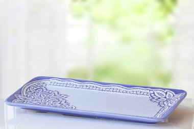 Boş masa ürünü. Masanın üzerindeki boş mavi porselen tabağın yakın plan bulanık perde arkası. Gıda ve ürün görüntüleme montajı şablonu.