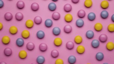 Pembe arka planda renkli renkli şekerler. Üst manzara, düz uzanma.