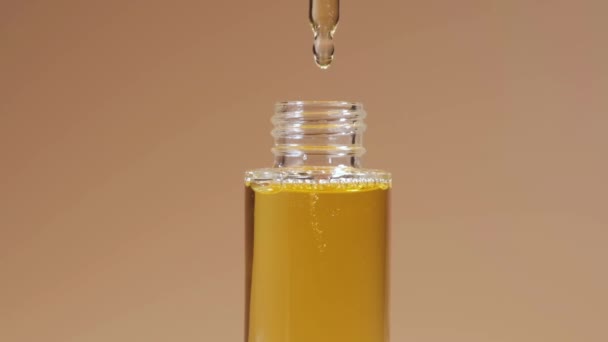 Olej z pipety do szklanej butelki na beżowym tle. — Wideo stockowe